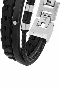 Pulsera trenzada de cuero negro con acentos de acero inoxidable plateado y un cierre pulido, que destaca texturas y acabados distintos.