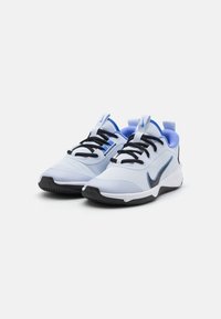 Hvide og lyseblå atletik sko med sorte snørebånd og en tekstureret overdel. Har en sort ydersål og et karakteristisk Nike-logo i sort.