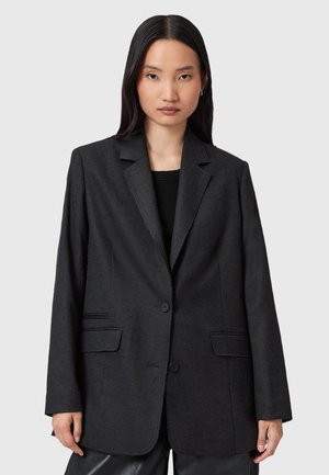 Blazer nero realizzato in tessuto testurizzato, con chiusura a un bottone, rever a ghillie e due tasche frontali. Design a taglio dritto.
