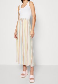 Letvægts, pastelfarvet maxi-nederdel med elastisk talje og snøre. Sammen med chunky lyserøde platforme. Glat tekstur.