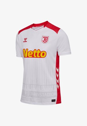 Camiseta de fútbol blanca y roja con el logo de Netto, el escudo del club RJ, el logo de hummel y un gráfico sutil del estadio en la parte inferior.