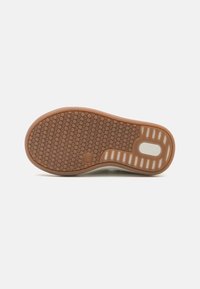 Brown rubber sole with a textured, dotted pattern; features a white accent with horizontal stripes on the side for enhanced grip.