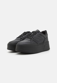 Sneakers platform neri con una tomaia in materiale sintetico liscio, design con lacci, accenti laterali testurizzati e una suola spessa e rigata.