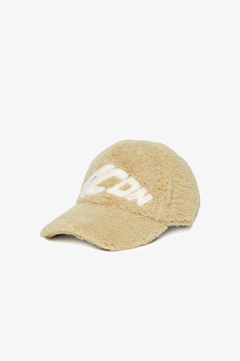 Beige cap made of soft, textured fabric with a slightly curved brim, featuring a prominent white logo embroidered on the front.