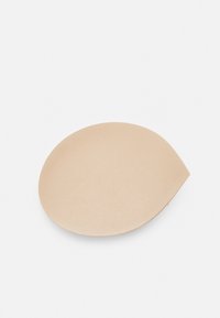 Almohadilla de silicona nude con una textura suave, forma ovalada y un ligero afilado en un borde, diseñada para mayor comodidad y uso discreto.