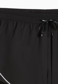 Schwarze Sportshorts mit glatter Textur, ausgestattet mit einem Netzbund, Kordelzug und weißen Akzenten am Saum.