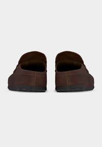 Ζευγάρι καφέ καστόρινων παπουτσιών χωρίς κορδόνια με μαύρες λαστιχένιες σόλες, εμφανιζόμενα από πίσω πάνω σε απλό ανοιχτό γκρι φόντο.