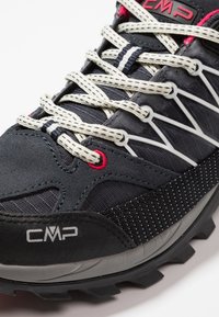 Ciemnoszare buty trekkingowe z teksturowaną skórą zamszową, białymi i czarnymi sznurówkami w wzory oraz trwałą gumową podeszwą. Widoczne logo CMP.