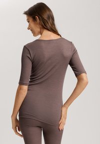 Top in jersey marrone a coste con maniche corte, scollatura rotonda e design aderente, che mostra una texture liscia e dettagli di cucitura minimi.