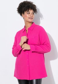 Fuchsiefarbenes Hemd mit Knopfleiste aus strukturiertem Stoff, mit langen Ärmeln, Brusttaschen und einem lockeren Schnitt. Geeignet für schichtweise Styling.