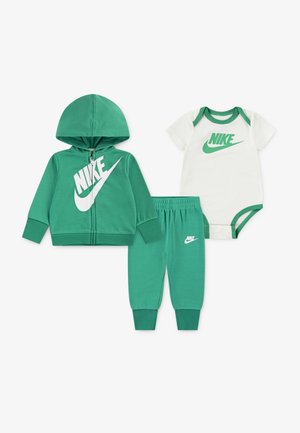 Zeleni Nike otroški komplet, ki vključuje zadrgo pulover s kapuco, dolge hlače in bodi s kratkimi rokavi, s prvim logotipom Nike v beli barvi.