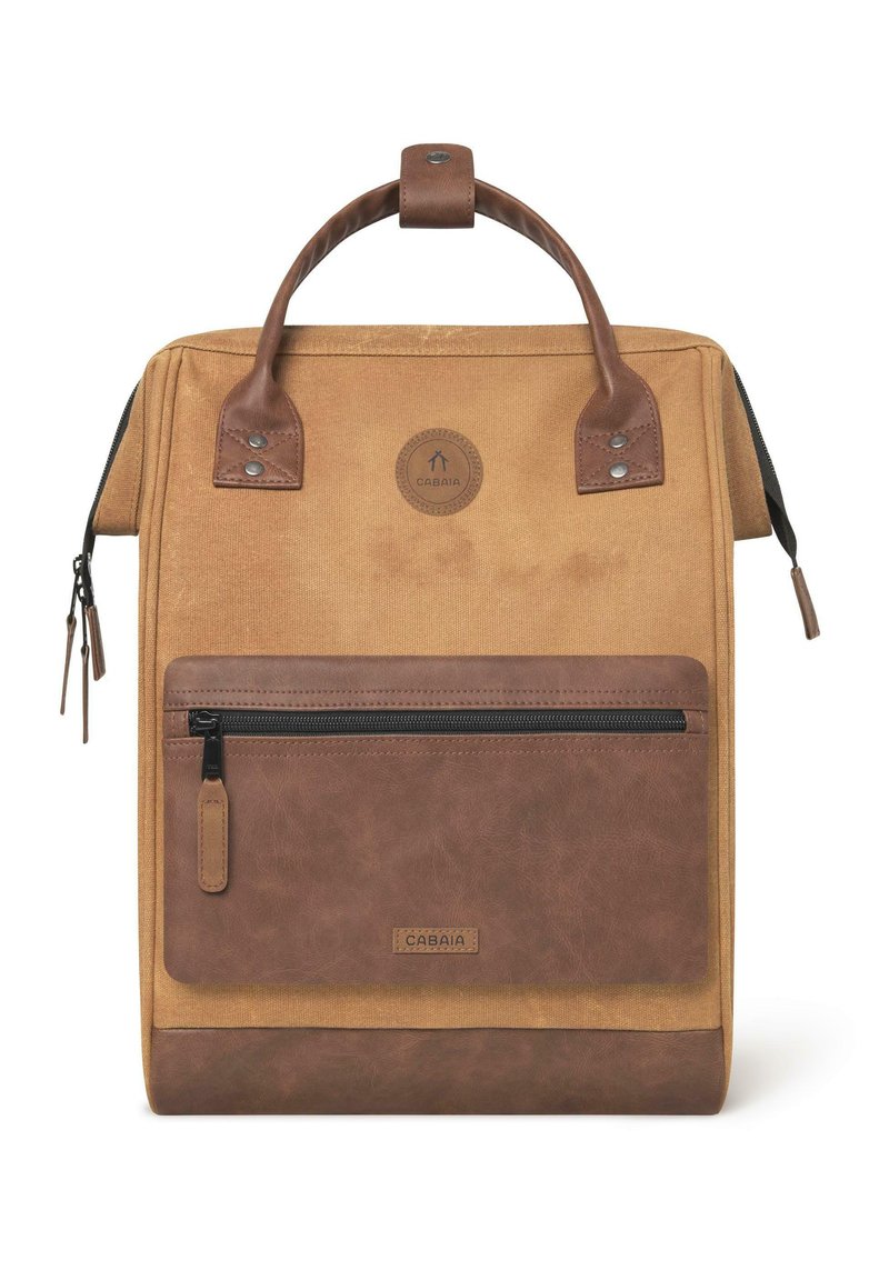 Sac à dos en toile beige avec des accents en cuir marron, doté d'une poignée supérieure, d'une poche zippée à l'avant et d'un patch logo rond. Détails des zips et des coutures.