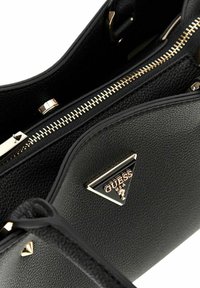Borsa a tracolla in pelle nera con minuteria dorata, dotata di chiusura con zip e accentazione a logo triangolare. Superficie texturizzata e design strutturato.
