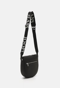 Borsa a tracolla nera in pelle con forma curvata. Presenta una tasca frontale con zip e una tracolla regolabile a fantasia in bianco e nero.