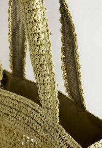 Borsa a tracolla in paglia intrecciata di colore verde chiaro. Presenta manici intrecciati texturizzati e una fodera in tessuto, offrendo un aspetto naturale e informale.