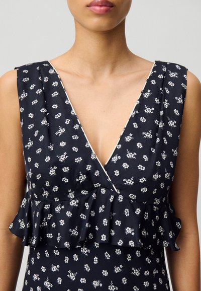 Vestido florido azul marino con un pronunciado escote en V, dobladillo corto con volantes y pequeños patrones de flores blancas. Confeccionado en una tela suave de textura lisa.