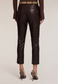 Bruine leren cropped broeken met een gladde textuur, met een aansluitend ontwerp en twee achterzakken. Draag met beige hoge hakken.