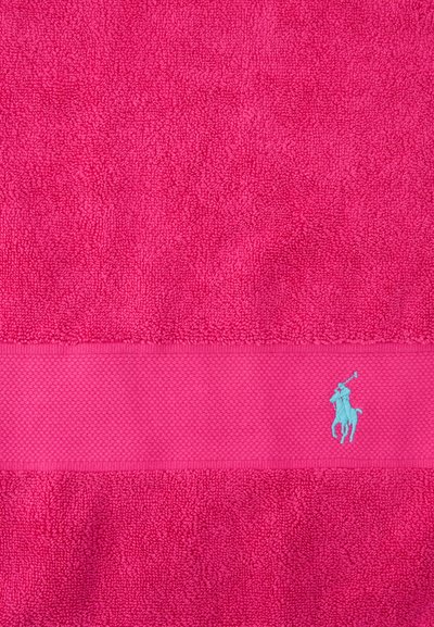 Bright pink textured towel with a horizontal band near the bottom featuring a small, light blue embroidered polo player logo.
