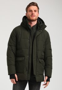 Giacca imbottita verde oliva con cappuccio, dotata di chiusura con zip, molteplici tasche frontali, dettagli neri e polsini a coste per il calore.