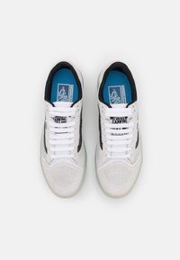 Valkoiset ja mustat lenkkarit, joissa on verkko- ja mokkamateriaaleja, rei'itetty varvasosa, valkoiset nauhat, vihreä läpinäkyvä pohja ja sininen sisäpohja.