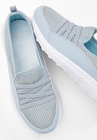 Scarpe sportive azzurro chiaro con tomaia in rete traspirante, design flessibile e suola in gomma testurizzata con cinturino elastico regolabile.