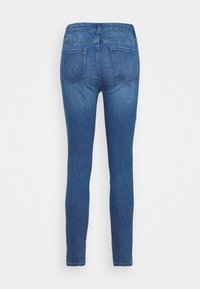 Jeans azul ajustados con dos bolsillos traseros, costuras visibles y una cintura de altura media, mostrados desde la parte trasera.