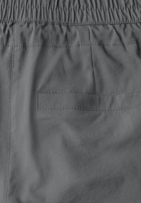 Tissu gris avec une texture lisse et un léger éclat. Présente une taille élastique et une seule poche arrière rectangulaire.