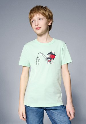 Tijelo mint zelene pamučne majice s grafikom lika koji ribari, s natpisom "TOMMY HILFIGER" ispisanim u crnoj boji. Kratki rukavi i okrugli izrez.