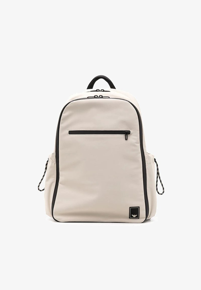 Zaino beige chiaro dal design elegante, con tasca frontale a zip, dettagli neri, spallacci regolabili e logo testurizzato.