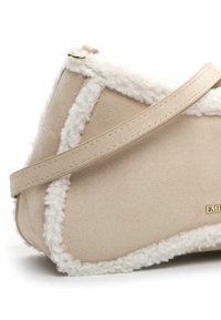 Borsa a spalla beige con bordi in morbido shearling e hardware dorato. Presenta un corpo in pelle liscia e una silhouette inclinata.