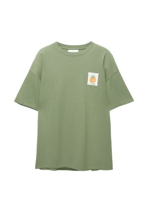 Olivgrünes übergroßes T-Shirt, kurze Ärmel, runder Ausschnitt, mit einem kleinen Patch mit einer stilisierten Gemüseillustration auf der Brust.