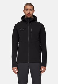 Czarna kurtka softshell z zamkiem, kapturem i zapinaną na zamek kieszenią na piersi. Posiada minimalistyczny design oraz logo na lewej stronie klatki piersiowej.