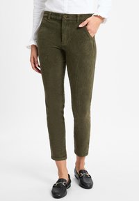 Olijf groene corduroy broek met een slim fit, met voorzakken en een subtiele ribbeltextuur, gedragen met zwarte instappers.
