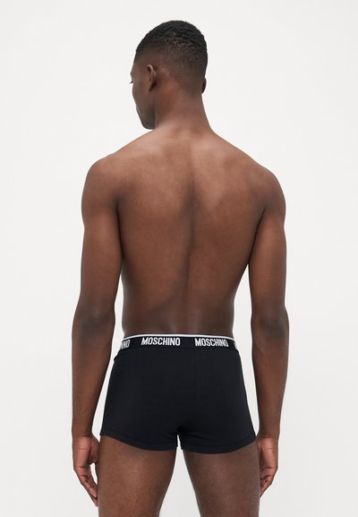 Black boxer shorts with a white Moschino logo waistband, made of soft material, featuring a fitted design and smooth texture.