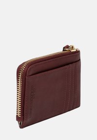 Bordeaux leren portemonnee met een gestructureerde afwerking, voorzien van een gouden rits en kaartsleuven aan één zijde, met een gegraveerd logo-detail.