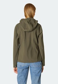 Chaqueta softshell verde oliva con capucha, diseño elegante y características ajustables, combinada con jeans de mezclilla azul claro.