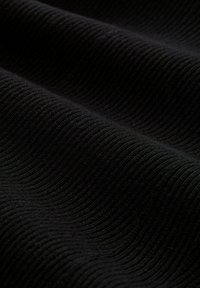 Schwarzer gerippter Stoff mit einer strukturierten Oberfläche. Der Stoff weist wellenförmige Linien auf, die horizontal verlaufen und Tiefe sowie Dimension erzeugen.