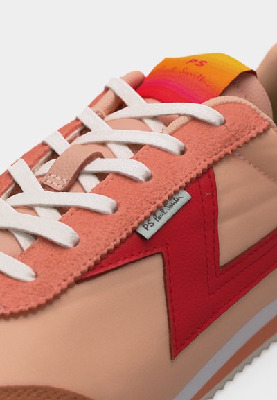 Κοντινό πλάνο ροζ και κόκκινου αθλητικού παπουτσιού με λευκά κορδόνια, που δείχνει λεπτομέρειες σουέτ επικάλυψης και ετικέτα PS Paul Smith στο πλάι.