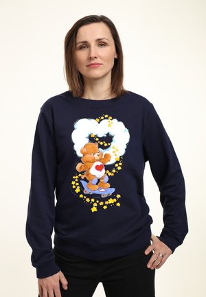 Marineblaues Sweatshirt mit einem grafischen Druck eines Bären auf einem Skateboard, umgeben von Wolken und gelben Sternen. Weiches Material aus Baumwollmischung.