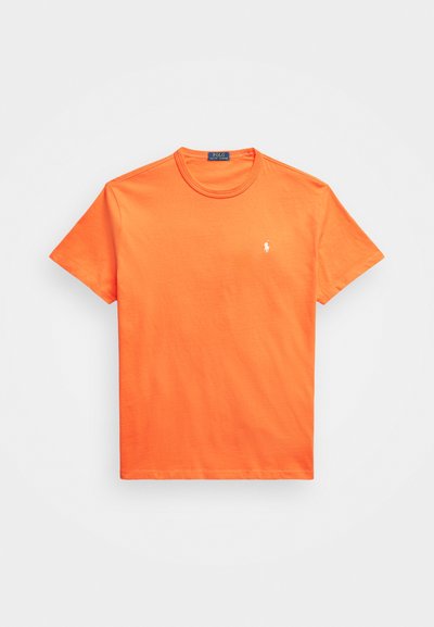 Orange bomulls t-shirt med rund halsringning, kort ärm och en liten vit logotyp på vänster bröst. Slät textur, klassisk passform.
