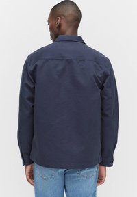 Marinblå, långärmad skjorta med krage, knappade manschetter och rak fåll, tillverkad av ett glättat, lättviktsmaterial.