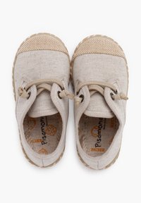 Scarpe in tela beige con una finitura texturizzata, punta rotonda e dettagli cuciti. Lacci di colore chiaro e suole in gomma con una sensazione naturale.