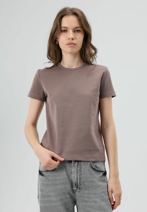 T-shirt met korte mouwen en ronde hals in licht mauve stof, met een gladde textuur en een aansluitend ontwerp, gecombineerd met grijze spijkerbroek.