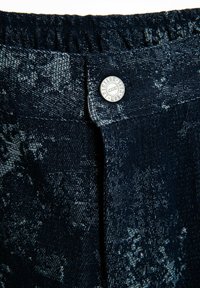 Tela de mezclilla oscura con un acabado texturizado, que presenta un diseño de patrón en gris claro. Cintura elástica con un detalle de botón plateado.