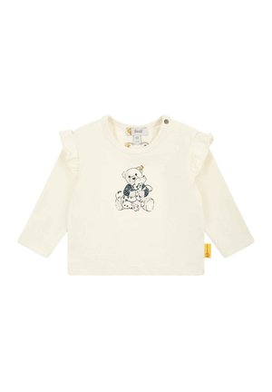 Long-sleeve cream shirt with ruffled shoulder accents and a bear graphic printed in dark colors. Features snap closure at the neck.