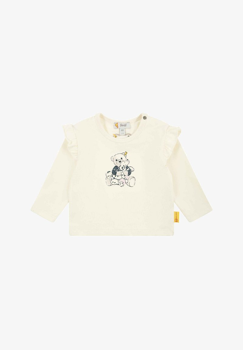 Long-sleeve cream shirt with ruffled shoulder accents and a bear graphic printed in dark colors. Features snap closure at the neck.