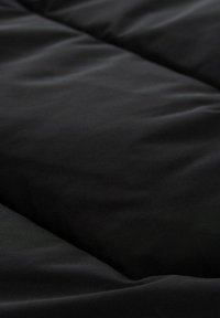 Housse de couette noire avec une texture lisse et un motif matelassé en losanges, présentant une construction solide et un design minimaliste.