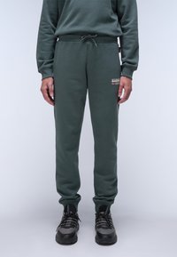 Grüne Baumwollmischung-Jogginghosen mit elastischem Bund, Kordelzug und Seitentaschen. Mit einem kleinen Logo-Patch am Oberschenkel.