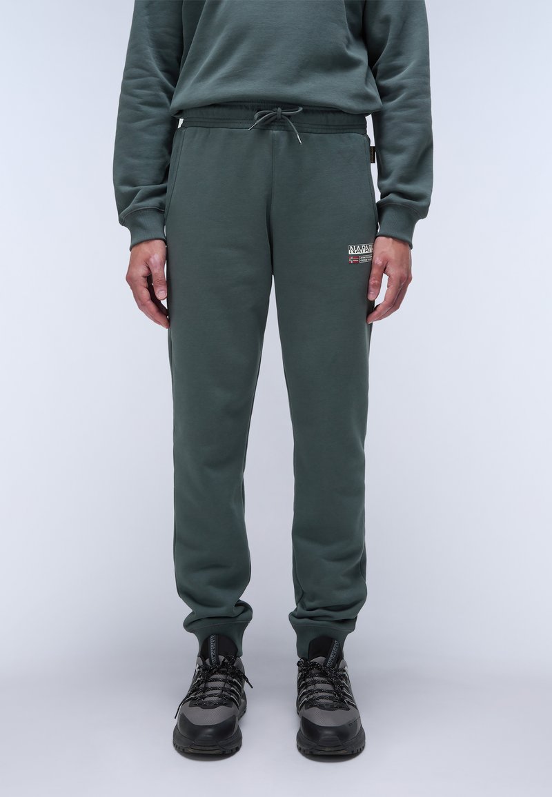 Grüne Baumwollmischung-Jogginghosen mit elastischem Bund, Kordelzug und Seitentaschen. Mit einem kleinen Logo-Patch am Oberschenkel.