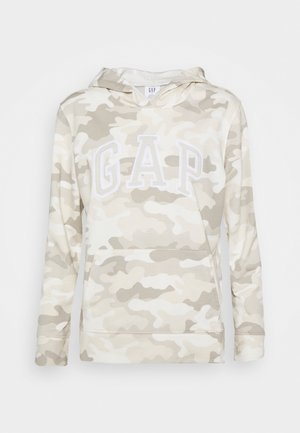 Sudadera con capucha con patrón de camuflaje en beige claro y blanco, y grandes letras blancas de GAP en el pecho, con bolsillo frontal tipo canguro.